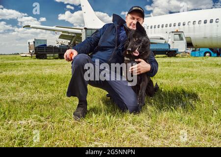 Male security officer hugging detection dog at airfield Stock Photo