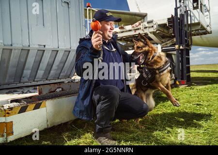 Security officer training detection dog in airfield Stock Photo