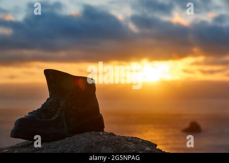 Finisterre Cape viewpoint at sunset with hiker boot mark. Pilgrimage Stock Photo