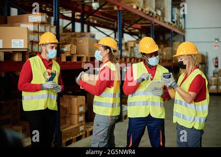 Diverse colleagues with gadgets working in storehouse Stock Photo