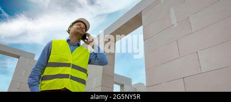 construction foreman talking on the mobile phone at building site. banner copy space Stock Photo