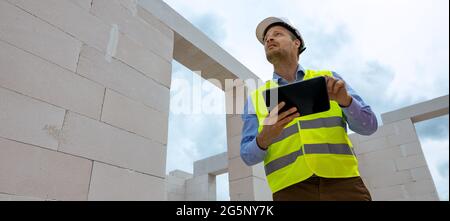 construction project monitoring - engineering supervisor working with digital tablet at building site. banner copy space Stock Photo