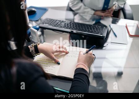 Unrecognized dentist woman wearing face mask due to covid19 working in her office and taking notes. Stock Photo