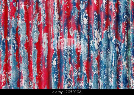 colorful motley peeled off red and blue paint layers on corrugated zinc coated steel sheet - full frame background and texture Stock Photo