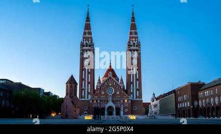 SZEGED, HUNGARY - MAY 18, 2021: View on the Votice Church and the people on the square in Szeged, Hungary at night. Stock Photo
