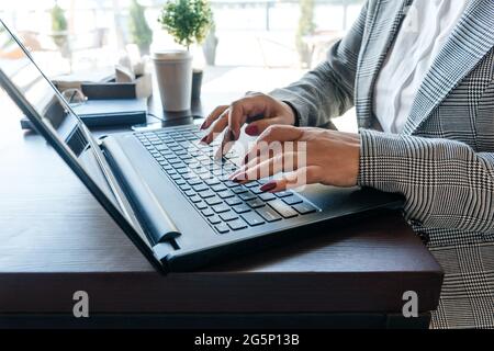 Womans hands typing in notebook in cafe. Window on background. Stock Photo