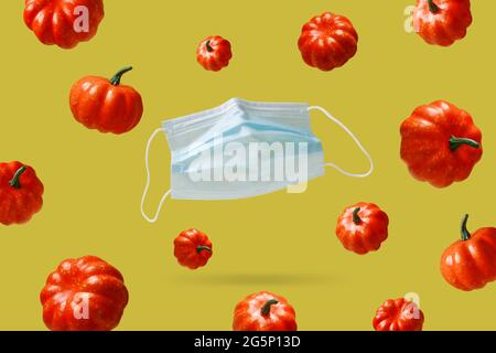 New normal season, autumn with flying protective mask. Flying pumpkins like symbol of autumn. Stock Photo