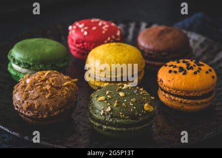 Colorful french macarons on a black plate, close up Stock Photo