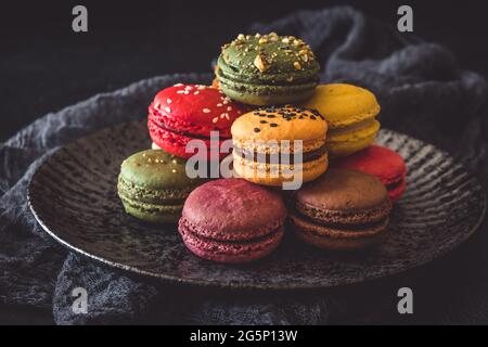 Colorful french macarons on a dark plate on black background Stock Photo