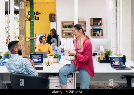 Young asian office worker talking with her african colleague and taking a break. Co-working concept. Stock Photo