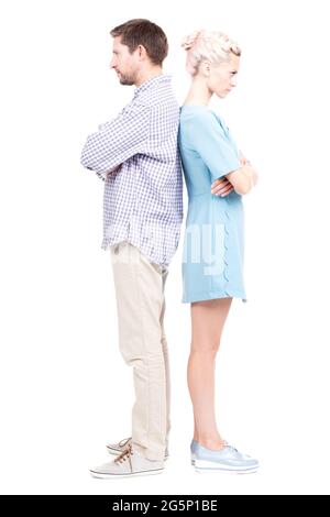 Vertical full length studio shot of modern Caucasian man and woman standing back to back with arms crossed angry at each other Stock Photo