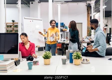 Multicultural work team having a meeting and using a white board in the office. Stock Photo