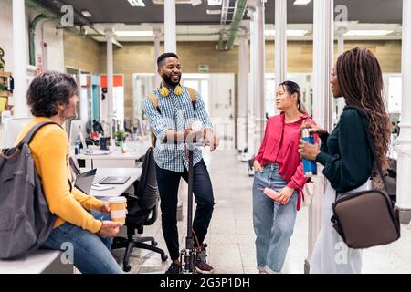 Multicultural office workers taking a break and having a conversation. The black man has an electric scooter. Stock Photo