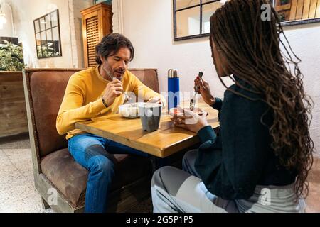 Coworkers eating lunch together in the office kitchen and talking. Co-working concept. Stock Photo