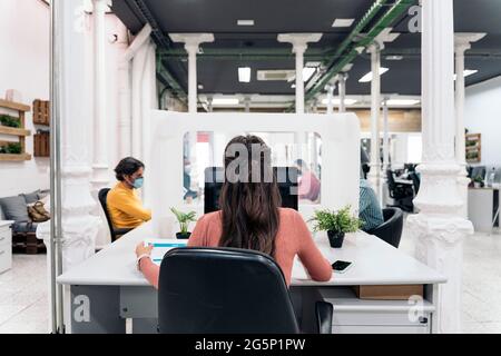 Diverse office workers sitting in a big desk and working with laptops. Co-working concept. Stock Photo