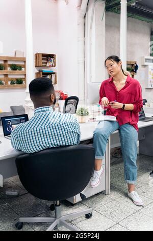 Young asian woman talking with her african coworker in the office. Stock Photo