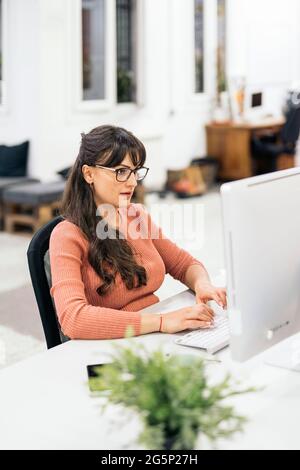 Focused office worker using computer and working in the office. Co-working concept. Stock Photo
