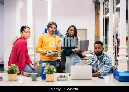 Diverse work team looking at camera and holding office equipment. Co-working concept Stock Photo