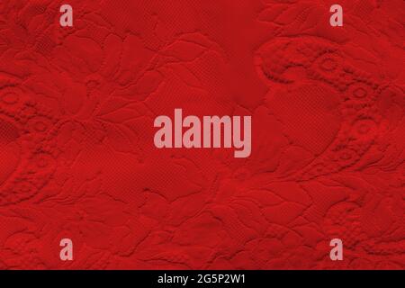 Red passionate lace on a silk fabric backing. Bright bridal wedding dress textile. Stock Photo