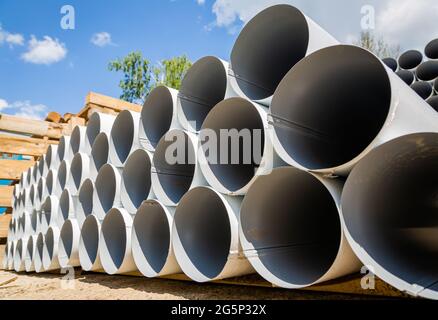 Downpipe warehouse. Steel pipes, parts for the construction of a roof drainage system in a warehouse. Stack of stainless steel pipes. Stock Photo