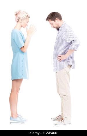 Vertical full length side view studio shot of angry young adult woman quarrelling with her husband, white background Stock Photo
