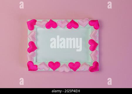 Empty photo frame decorated with hearts on a pink background, top view Stock Photo