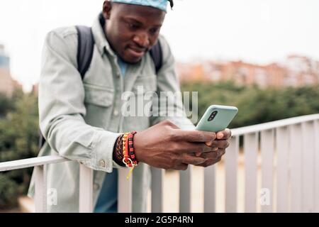 Happy and stylish african man in the street using his cellphone. Stock Photo