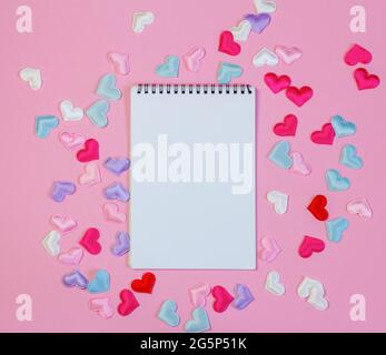 An open blank notebook on a pink background with hearts Stock Photo