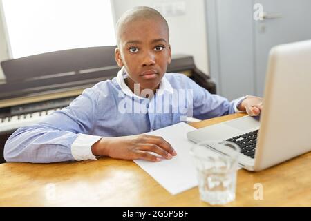 African boy studying online at laptop computer while homeschooling at home Stock Photo