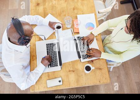 Young couple working online as a business team on laptop computer at home in the living room Stock Photo
