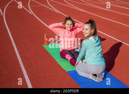 Your first step to fitness. School friends do situps on track. Physical fitness. Sports school Stock Photo