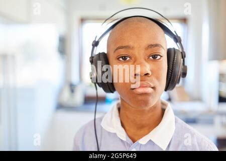 African boy homeschooling as a student with headphones doing distance class at home Stock Photo