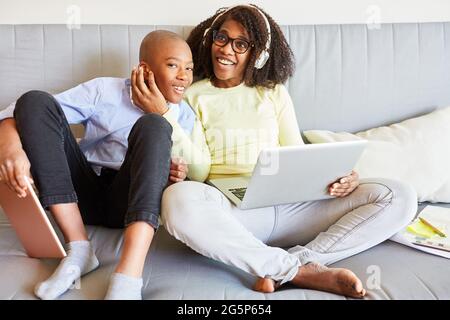 Mother and son on the sofa at home using a laptop computer while video chat online Stock Photo