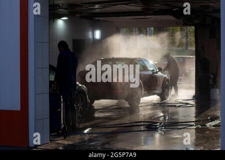 Car wash at a car wash. Workers wash their cars under the pressure of