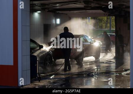 Car wash at a car wash. Workers wash their cars under the pressure of