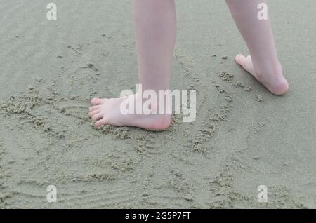 A child's feet playing in the sand on a beach