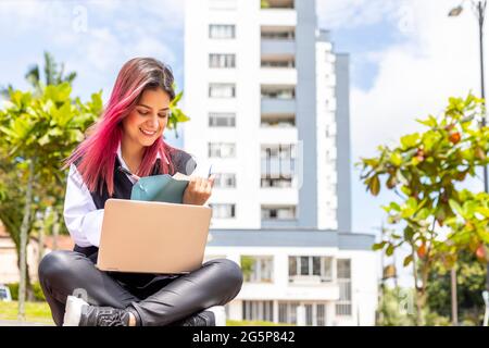 young latina woman taking notes while video meeting in laptop Stock Photo