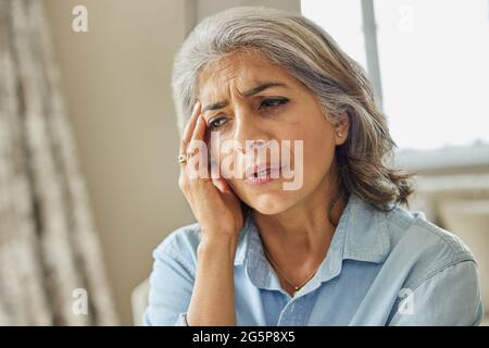 Mature Woman At Home Suffering From Headache Or Memory Loss Stock Photo