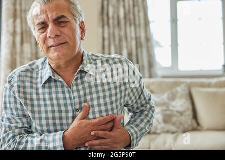 Mature Man Clutching Chest And Suffering Heart Attack At Home Stock Photo