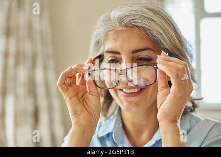 Smiling Mature Woman Trying On New Glasses At Home Stock Photo