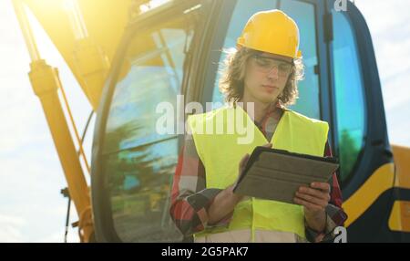 Excavator operator in hard hat using tablet pc. Stock Photo