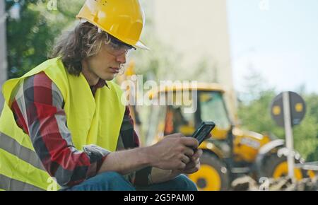 Tired male worker using smartphone on a break. Stock Photo