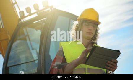 Excavator operator in hard hat using tablet pc. Stock Photo
