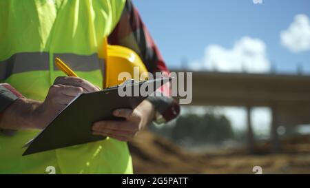 Builder with hard hat inspects construction site. Close-up. Stock Photo
