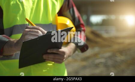 Builder with hard hat inspects construction site. Close-up. Stock Photo