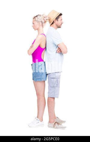 Vertical full length studio portrait of stylish young man and woman standing back to back with arms crossed after quarreling about something Stock Photo