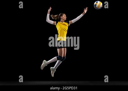 Female professional volleyball player with ball isolated on black studio background. The athlete, exercise, action, sport, healthy lifestyle, training Stock Photo