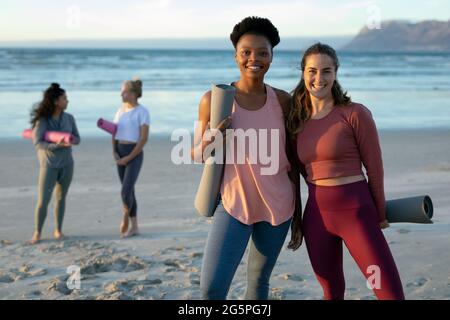 Portrait of two woman practicing yoga,standing at the beach taking break Stock Photo