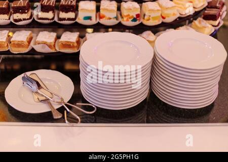 Two stacks of white plates for various desserts are prepared for guests. Breakfast at hotel. Festive event. Sweet buffet. Rest and travel. Taste and p Stock Photo