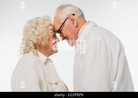 elderly couple gently touching with heads isolated on white Stock Photo